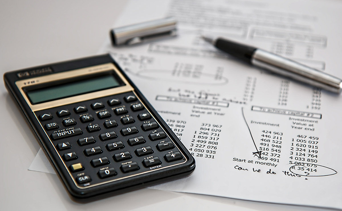 A financial calculator and a pen resting on a printed investment worksheet