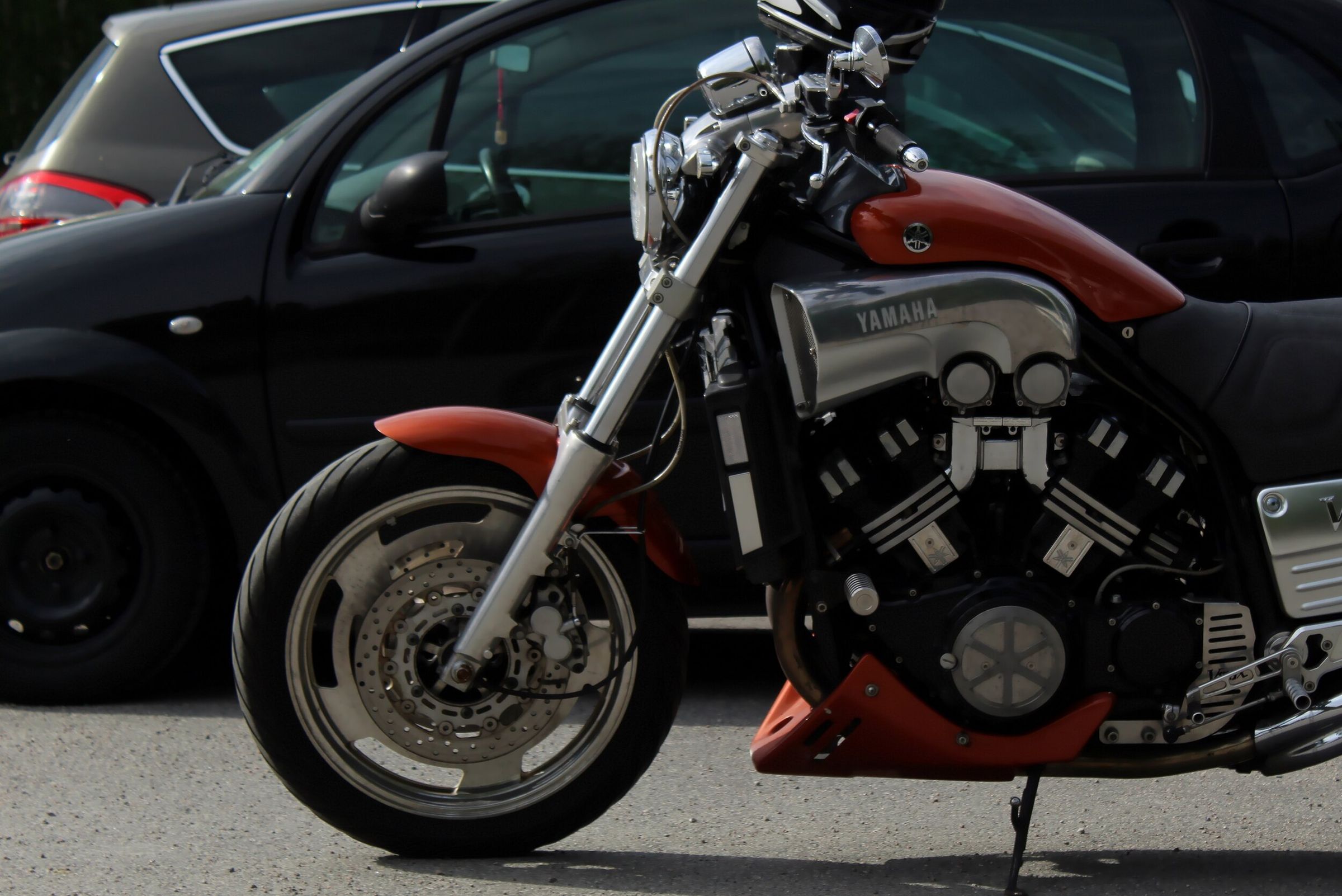 A red Yamaha motorcycle parked in front of a black car