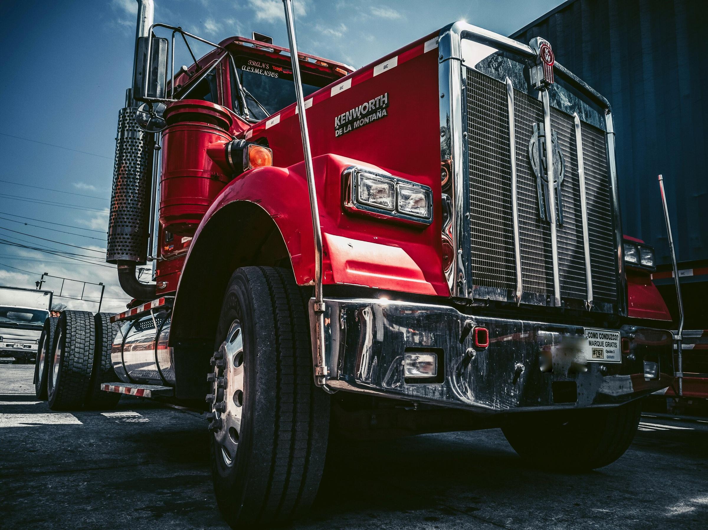 The front of a red Kenworth semi truck with a chrome grille