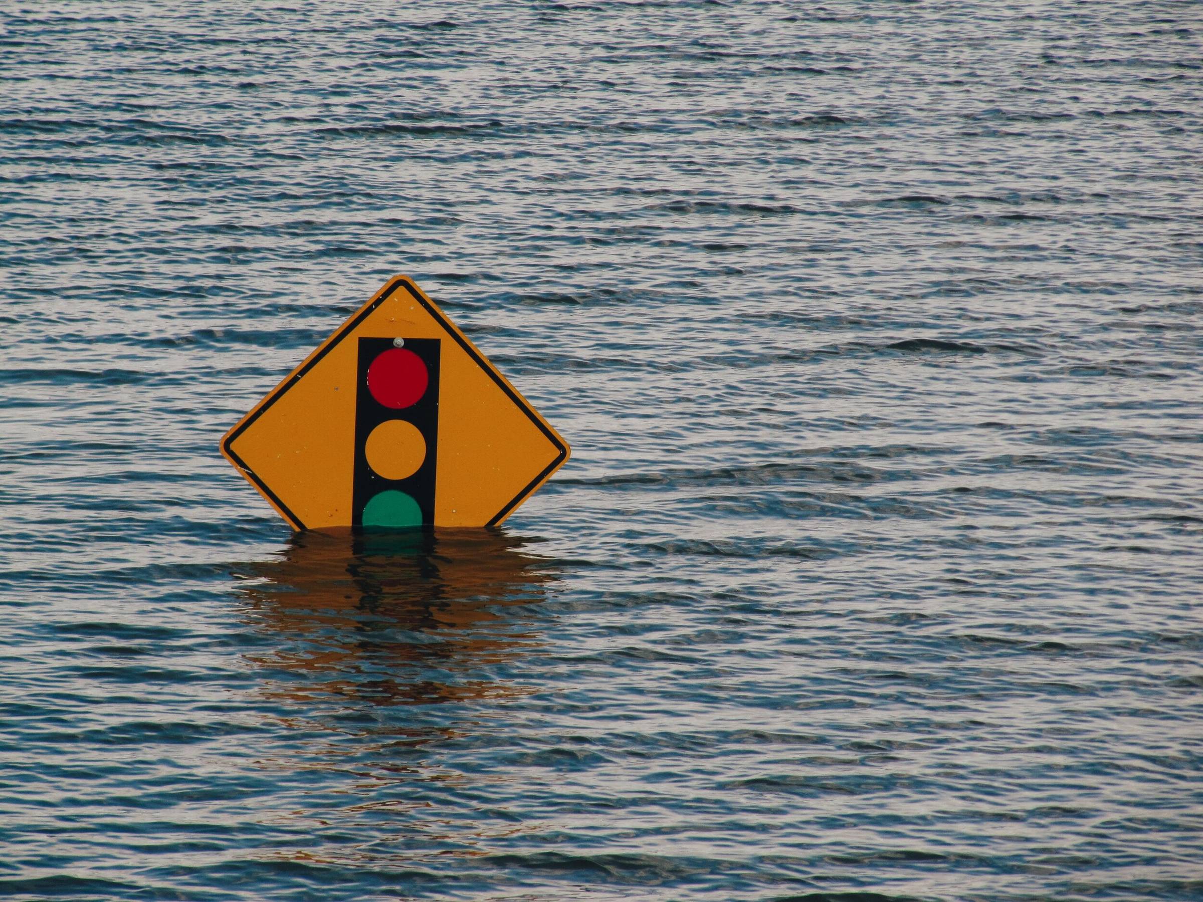 A traffic-signal warning sign half under floodwater