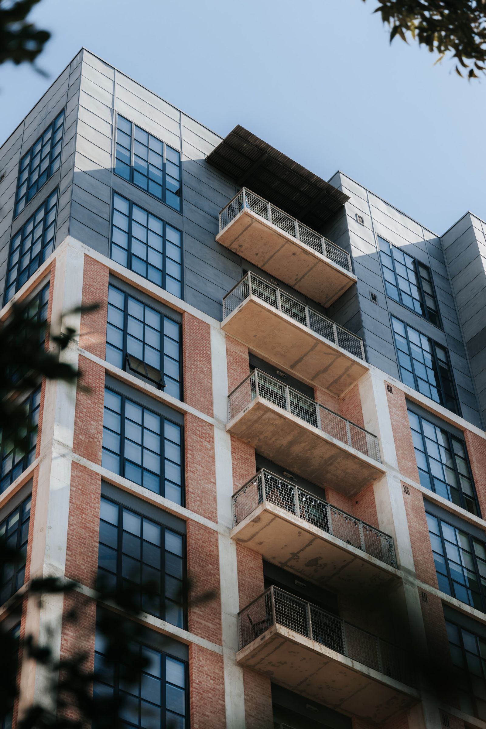 An apartment building of brick and gray panels with stacked balconies